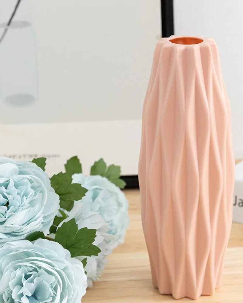 Pink textured vase with floral arrangement on a wooden surface