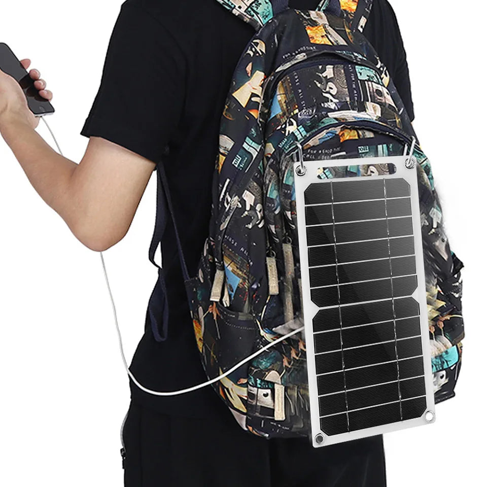 Person with a backpack featuring a solar panel attached, holding a smartphone.
