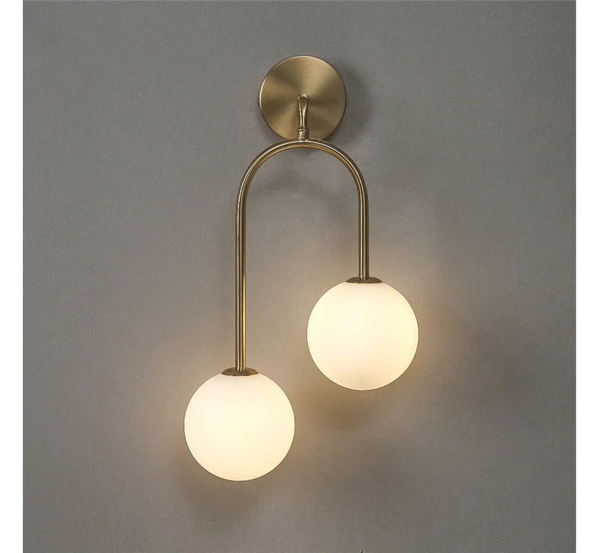 Wall-mounted light fixture with two round glass shades on a gray background