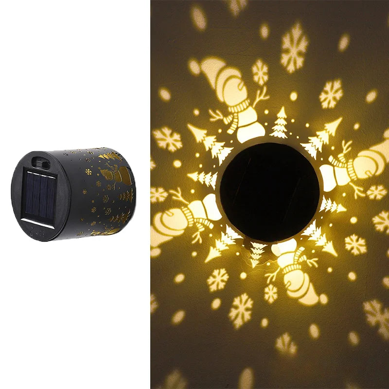 Solar-powered outdoor light projector with snowman and tree design on a dark background