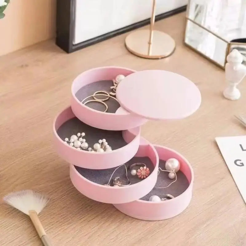 Pink jewelry organizer with three tiers on a wooden surface.