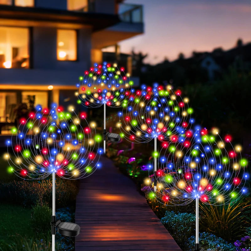Colorful outdoor light trees on a pathway in front of a house at night.