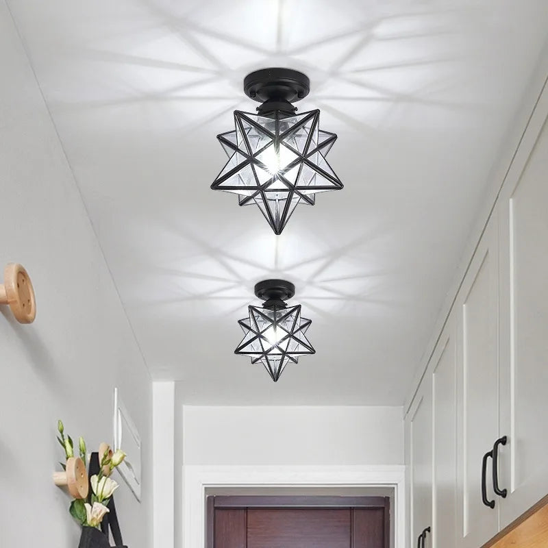 Two black geometric ceiling lights in a hallway with white walls and wooden doors.