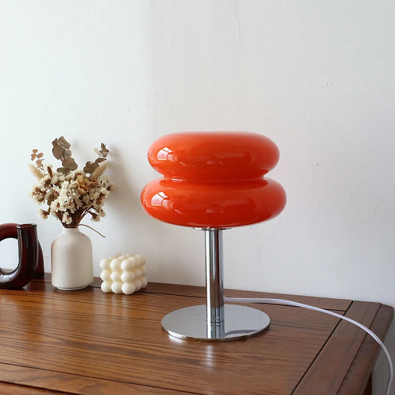Red stool with a white vase and decorative items on a wooden surface.