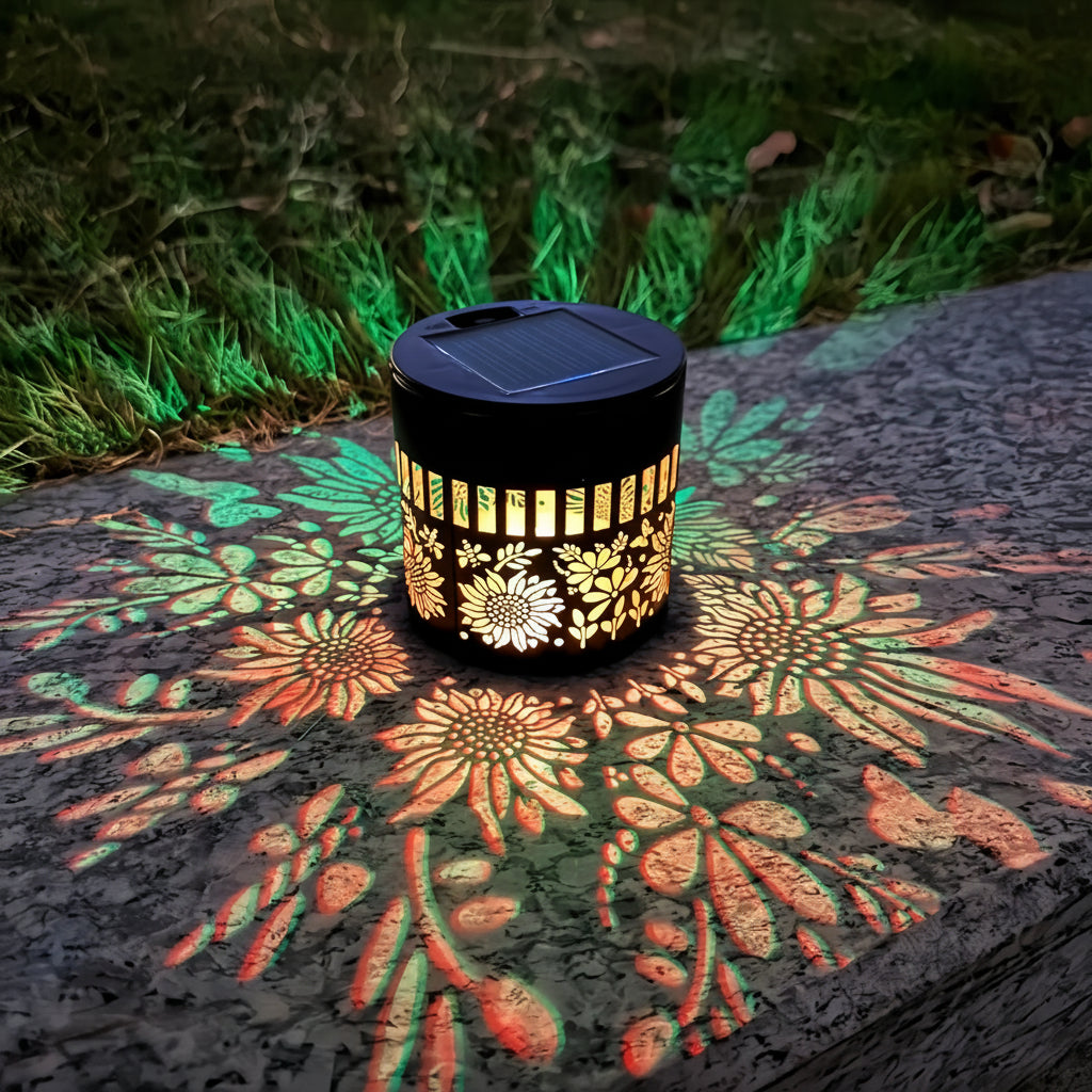 Solar-powered decorative lantern with floral patterns on a stone surface at night.