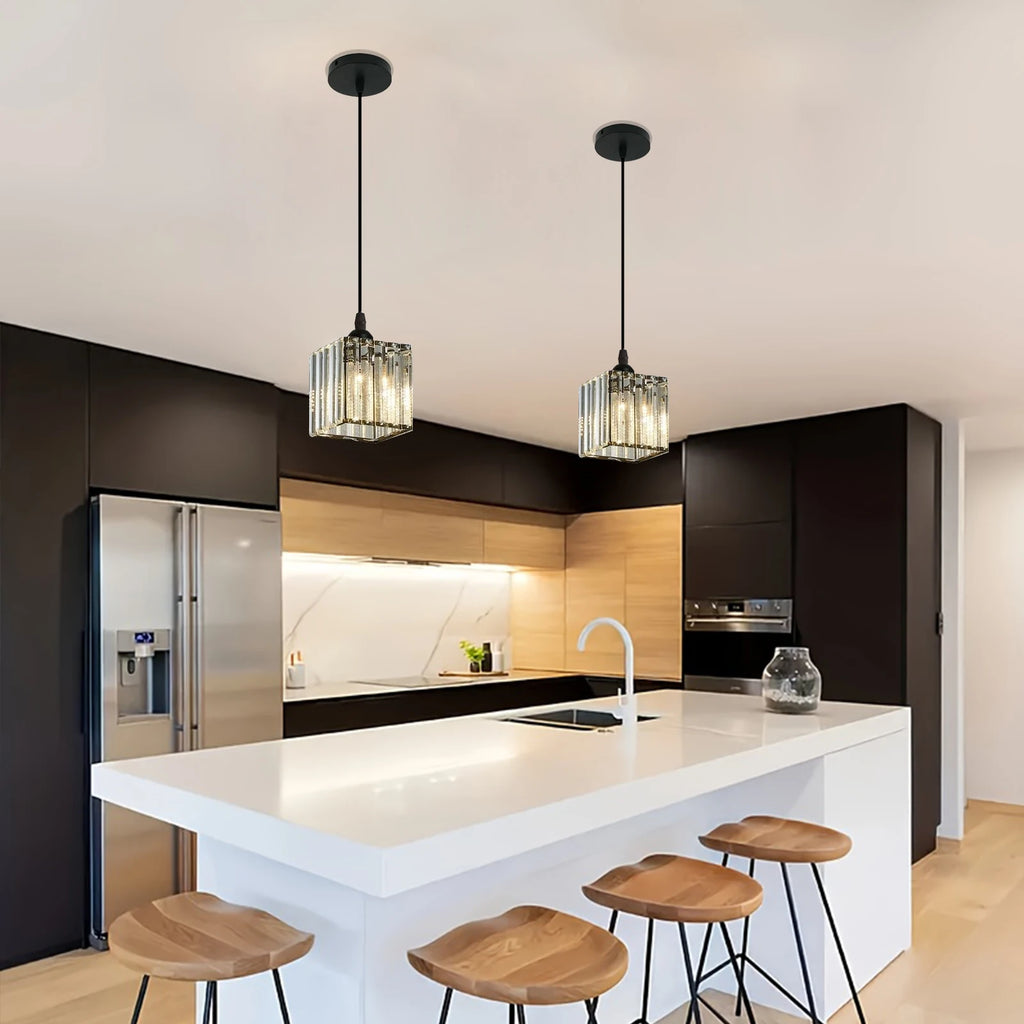 Modern kitchen island with a white countertop, dark cabinetry, stainless steel appliances, two hanging glass pendant lights, and four wooden bar stools.