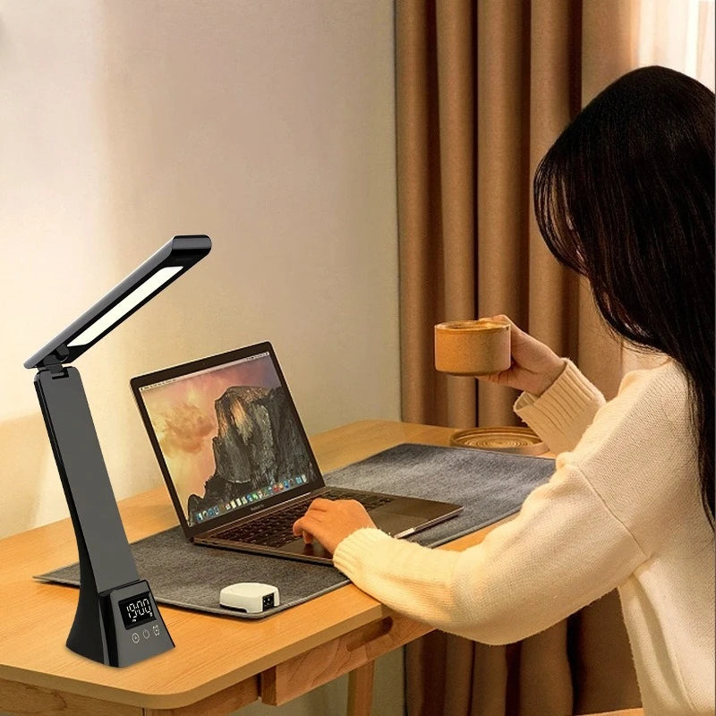 Person using a laptop with a desk lamp and a mug in a cozy room.