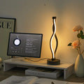 Modern desk setup with a computer monitor, lamp, and books on a wooden surface.