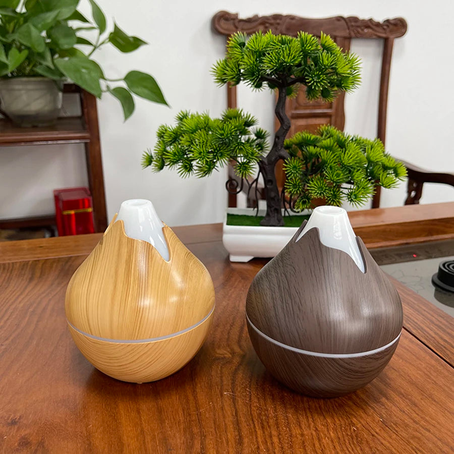 Two wooden diffusers on a table with plants in the background