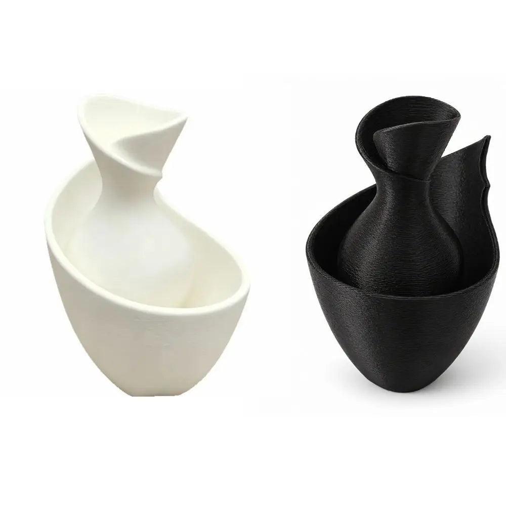 Two modern sculptural bowls or vases shown side by side on a white background: one matte white on the left and one matte black on the right.