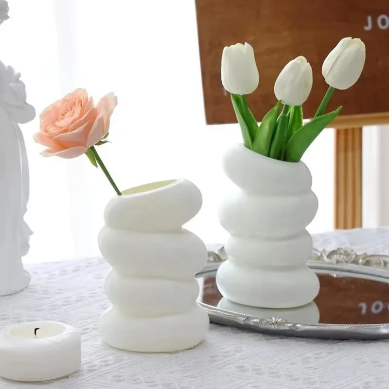 Two white ceramic vases with flowers on a table