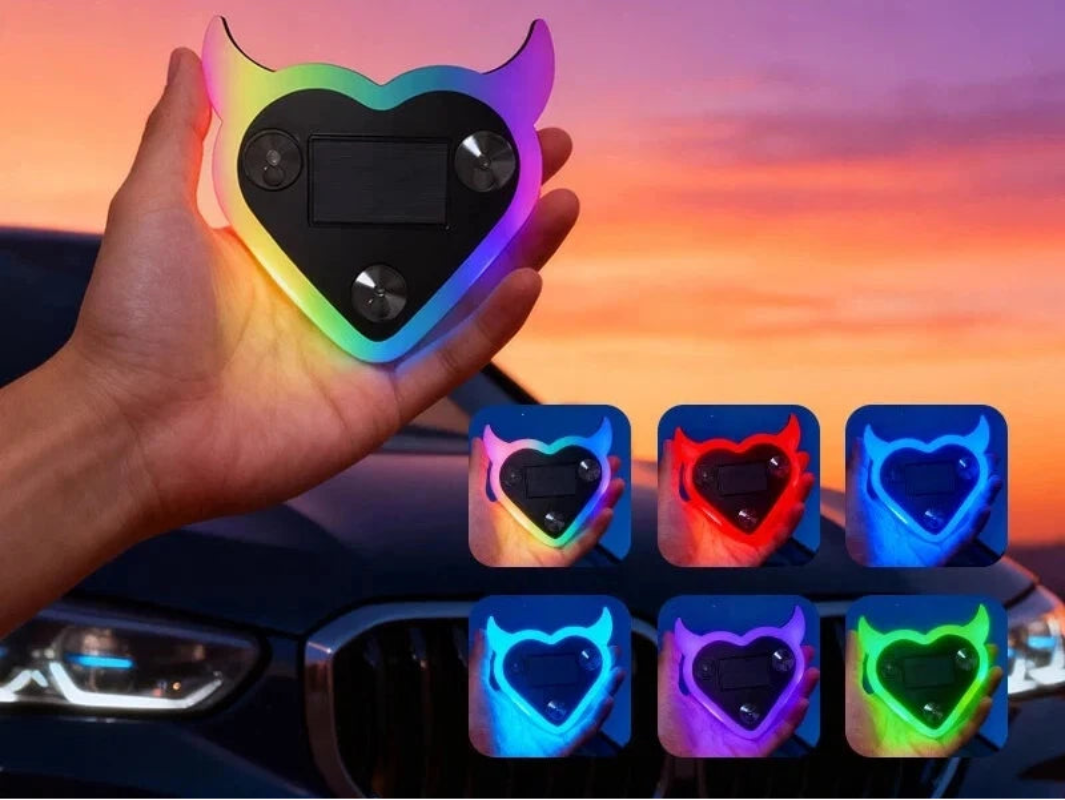 Heart-shaped colorful car window sticker held by a hand with sunset background