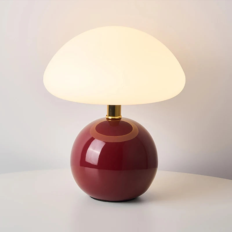 Table lamp with a red base and white shade on a neutral background