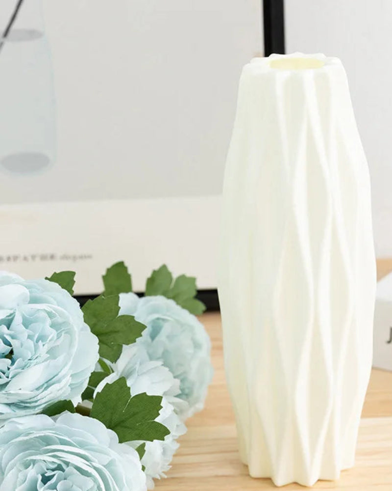 White vase with measurements next to light blue flowers on a wooden surface