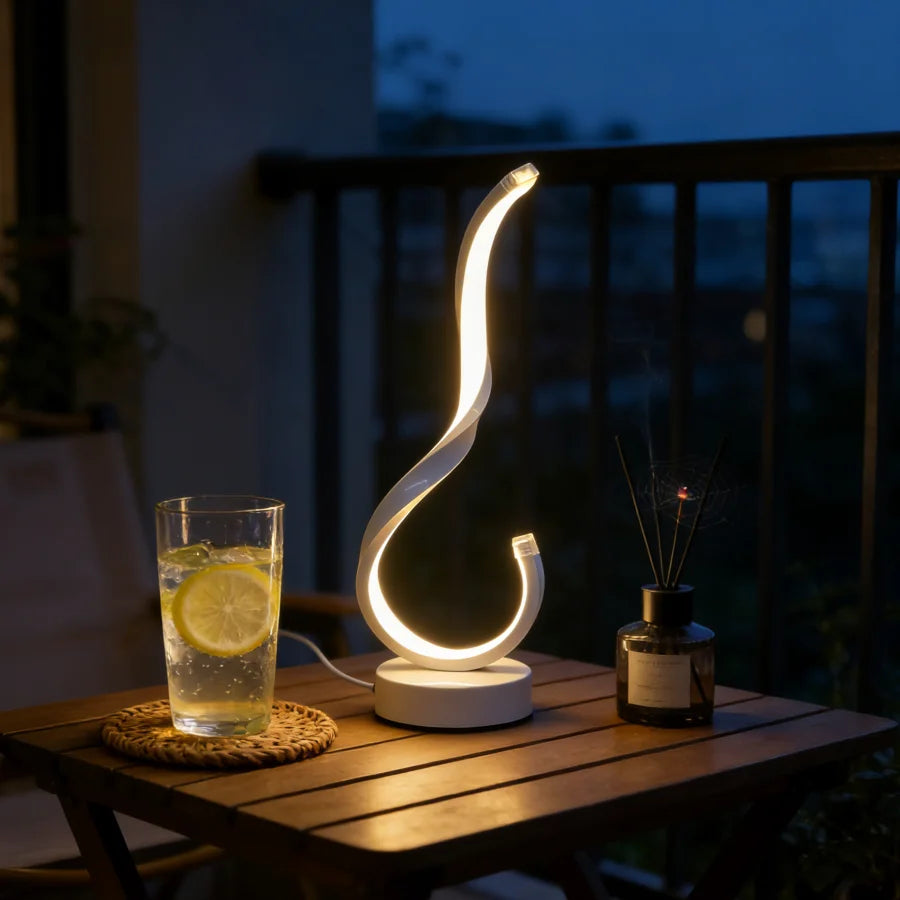 Modern lamp with a glass of lemonade on a wooden table at night.