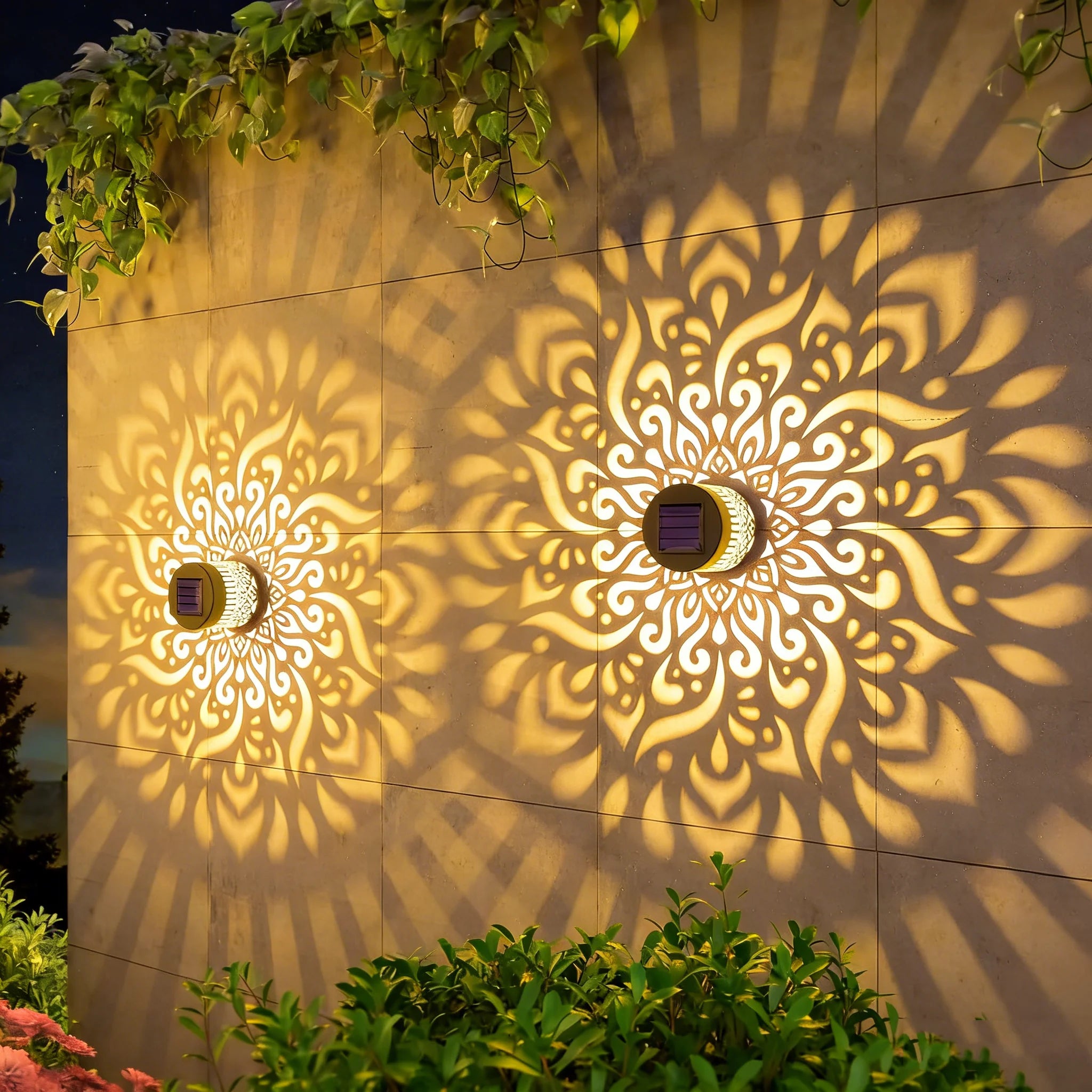 Decorative wall with mandala patterns cast by solar lights, surrounded by greenery.