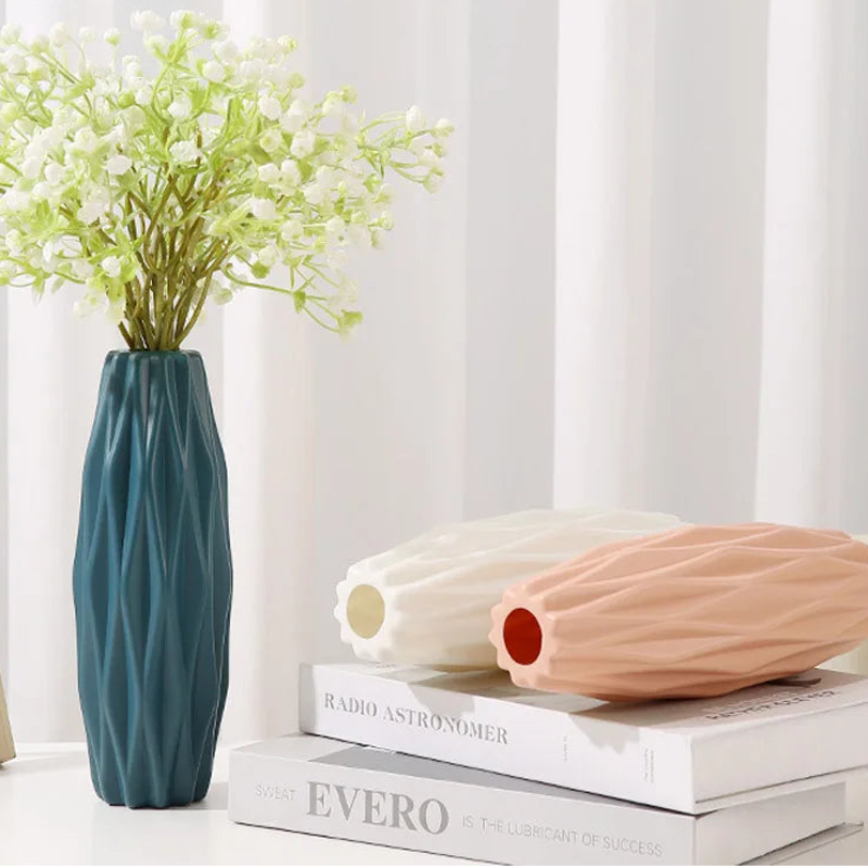 Decorative vases and books on a white surface with a light gray curtain background