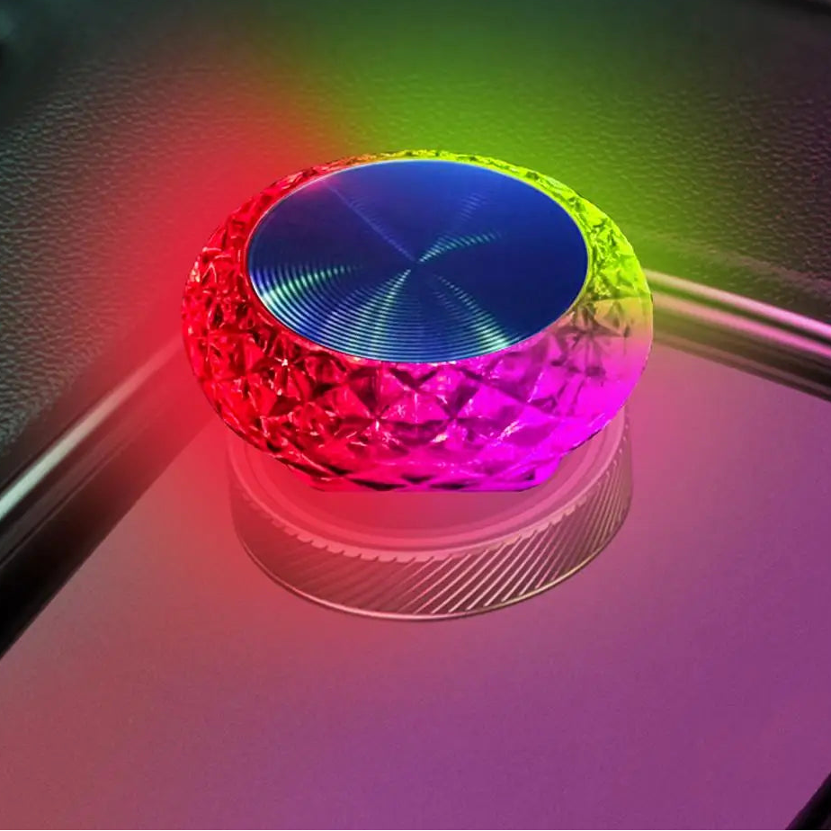 Colorful light-up object on a reflective surface with a blurred background