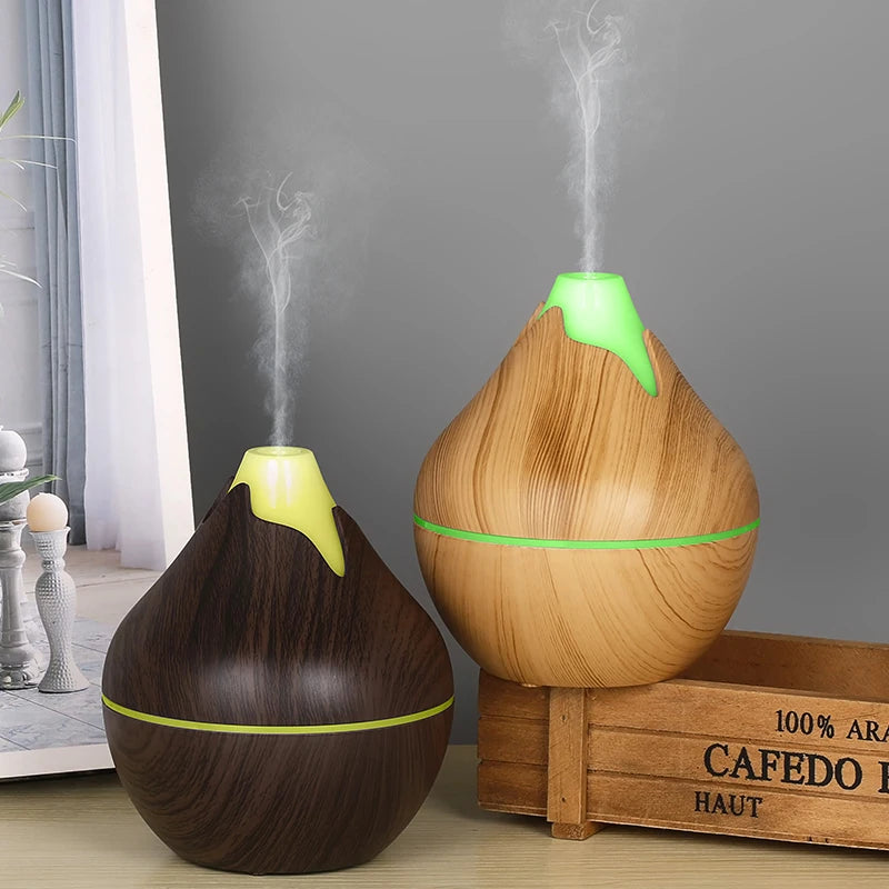 Two wooden diffusers emitting steam on a wooden surface with a gray wall in the background.