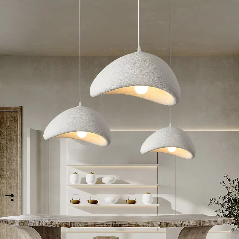 Three modern pendant lights hanging above a dining table in a kitchen.