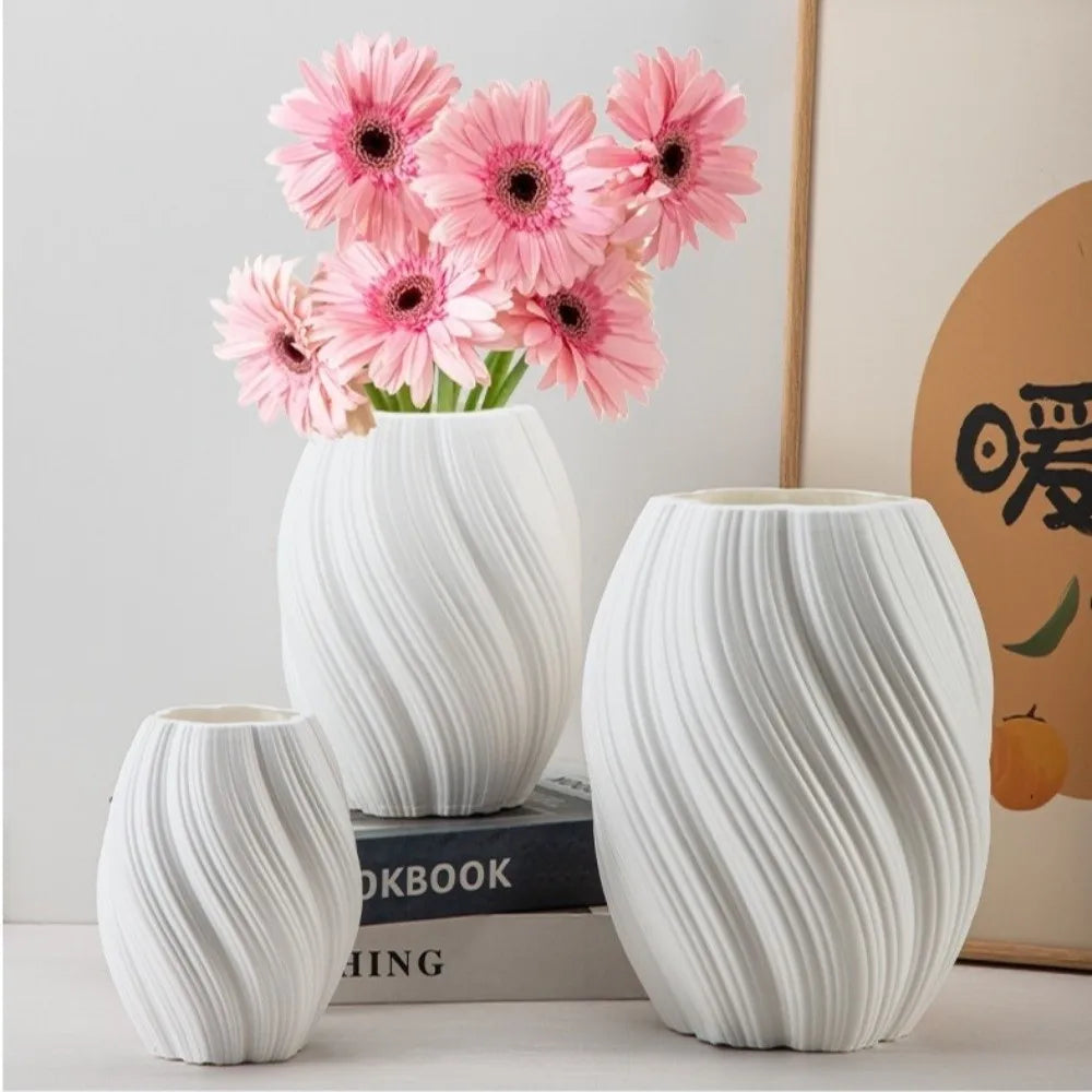 Set of three white marbled vases with pink flowers on a light gray background