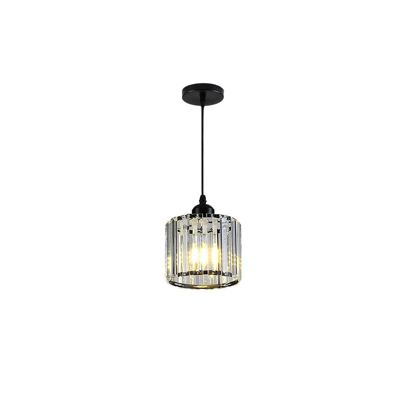 A single hanging pendant light fixture with a black ceiling canopy and cord, a cylindrical clear faceted glass shade, and warm light visible inside.