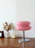 Pink stool with a round design on a wooden surface against a white wall