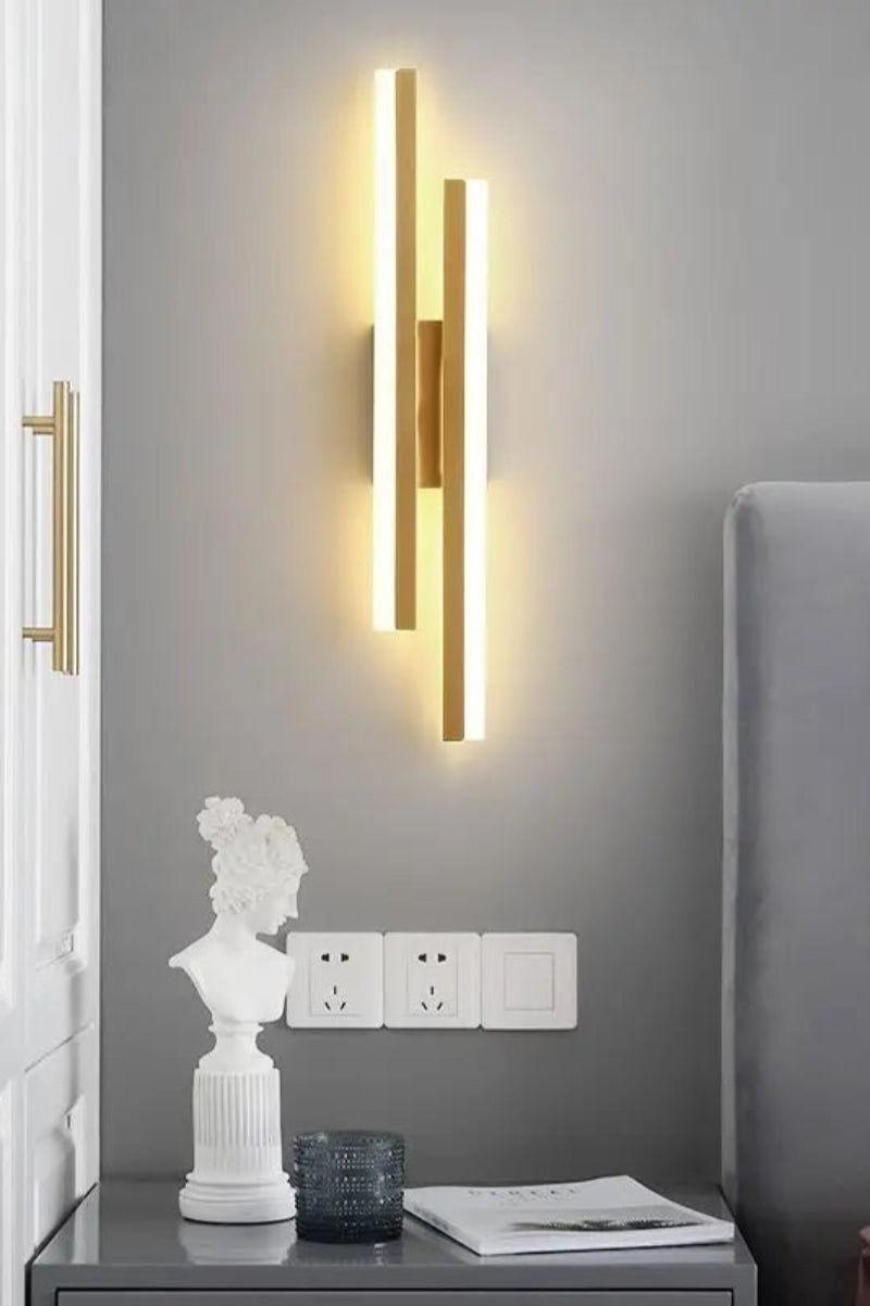 Modern wall sconce on a gray wall with decorative items on a table.