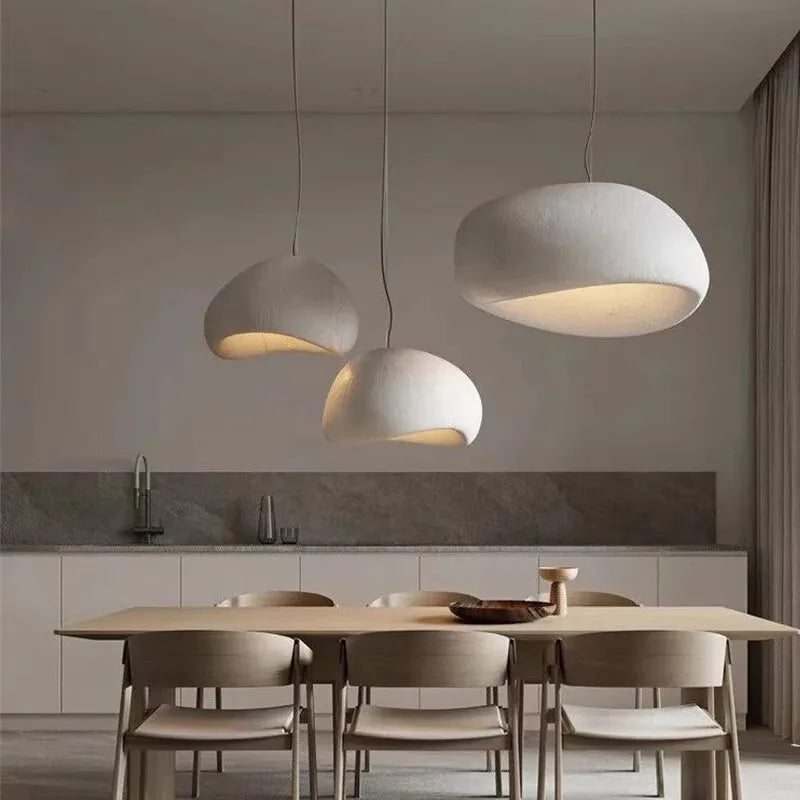 Modern dining area with pendant lights and a kitchen in the background.