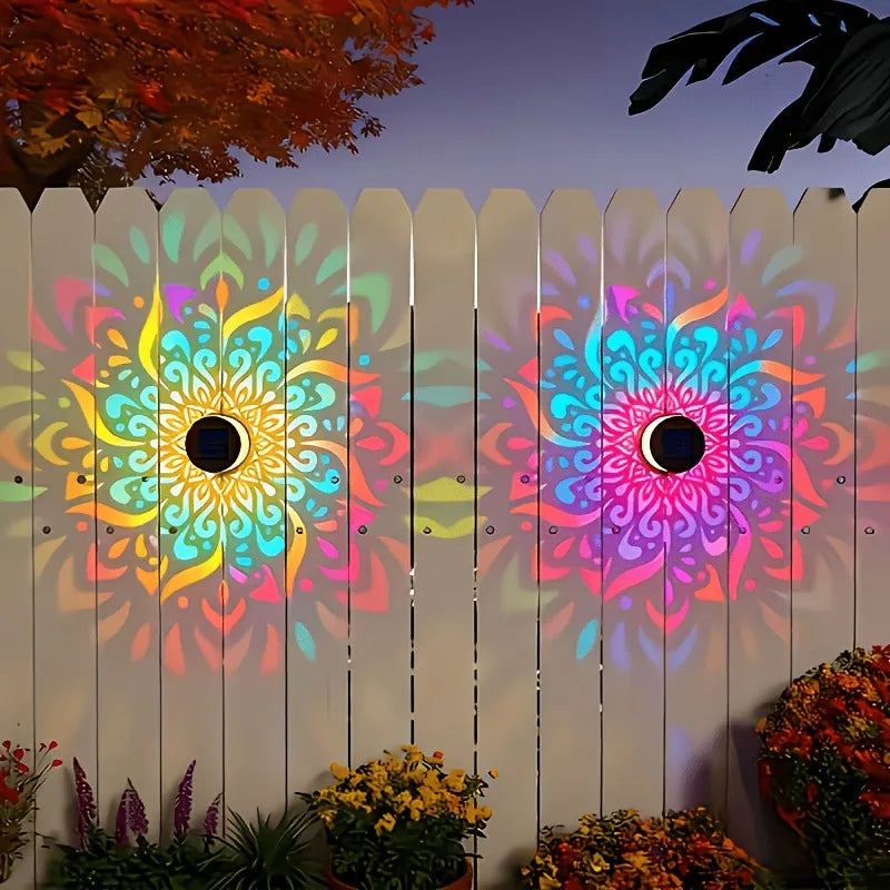 Colorful mandala designs on a wooden fence with plants in the foreground.