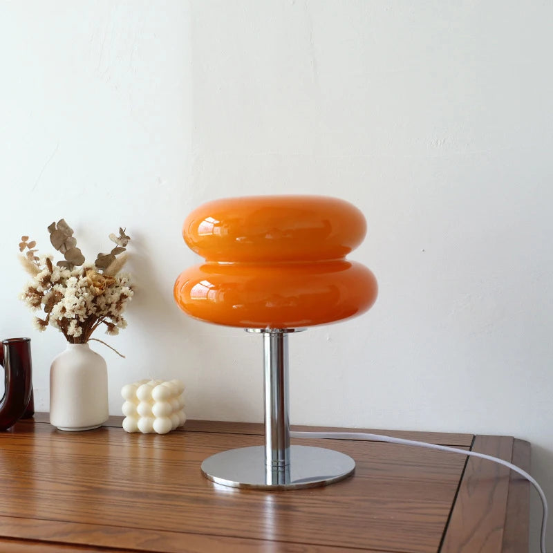 Orange table lamp on a wooden surface with decorative items in the background