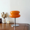 Orange table lamp on a wooden surface with decorative items in the background