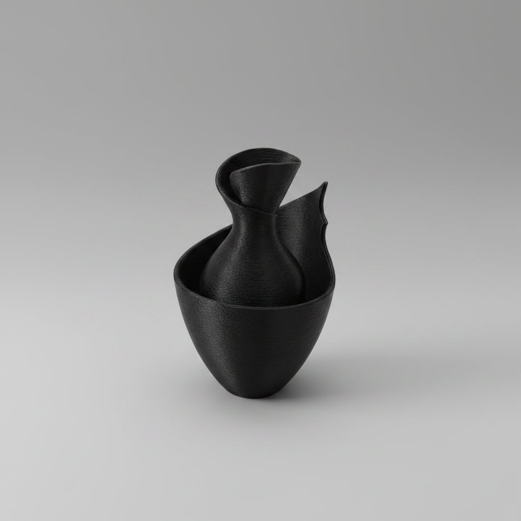 A modern black ceramic vase with a sculptural, organic shape and a textured matte finish, shown on a solid white background.