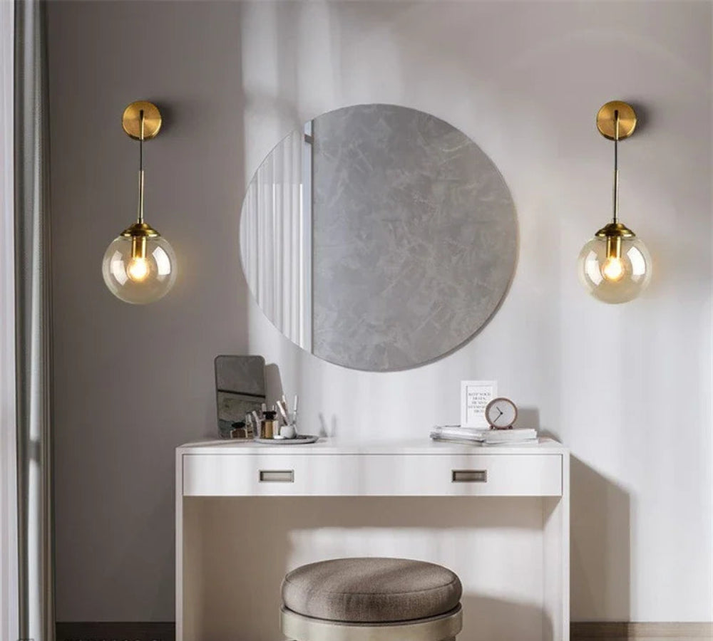 Modern vanity setup with round mirror, lights, and stool in a minimalistic room.