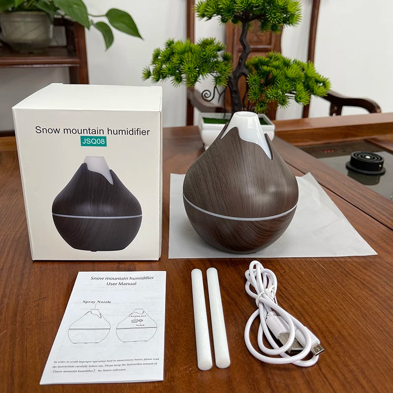 Snow mountain humidifier with packaging, manual, and accessories on a wooden table.