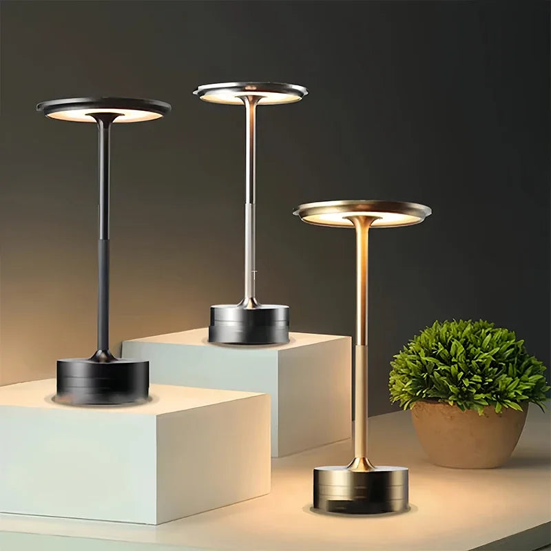 Three modern outdoor lamps on geometric platforms with a plant in the background.