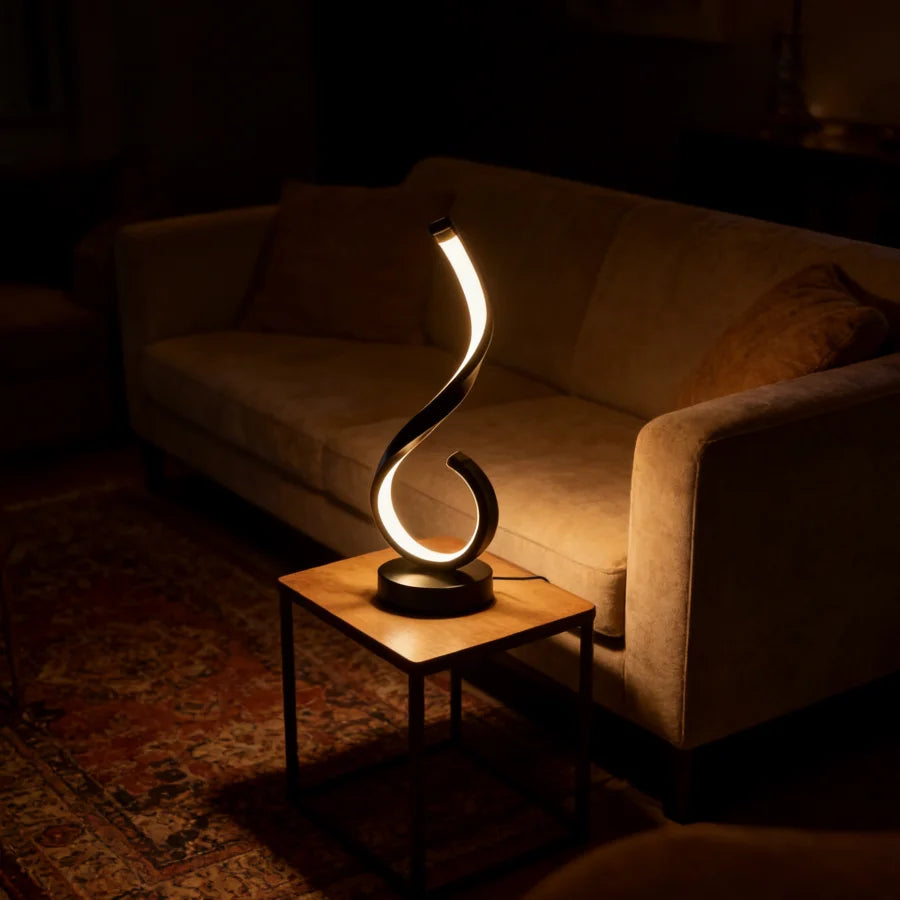 Modern table lamp with a curved design on a side table in a dimly lit room.