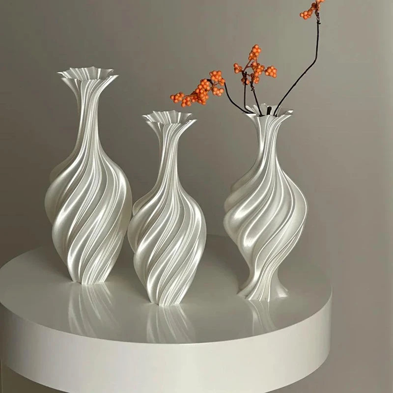 Three decorative vases with wavy design on a white platform against a gray background