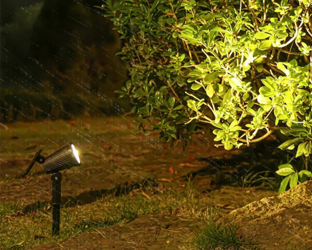 Outdoor garden light fixture illuminating a pathway with surrounding greenery.