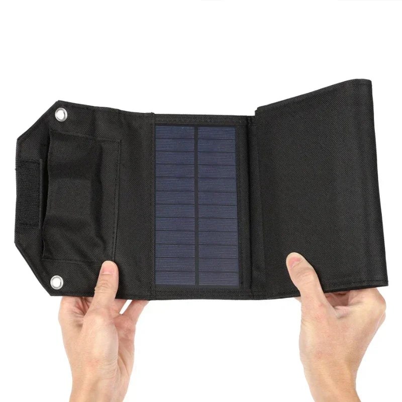 Black solar panel with a textured surface held by two hands on a white background