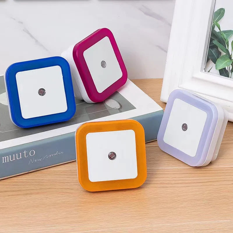 Four square night lights in blue, pink, orange, and purple on a wooden surface.
